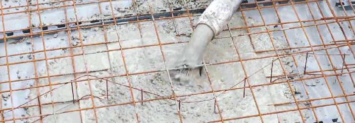 Mit einem Schlauch wird Beton auf die Drahtgitter gegossen.